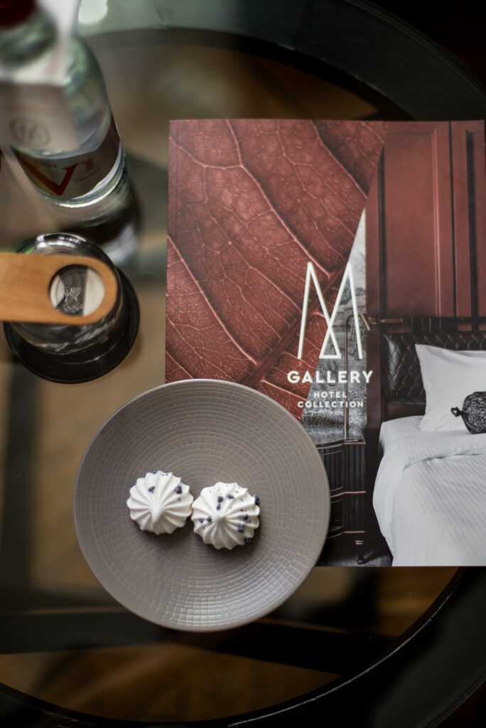 Deux meringues sur une assiette, une bouteille d’eau et une brochure MGallery disposées sur une table en verre.